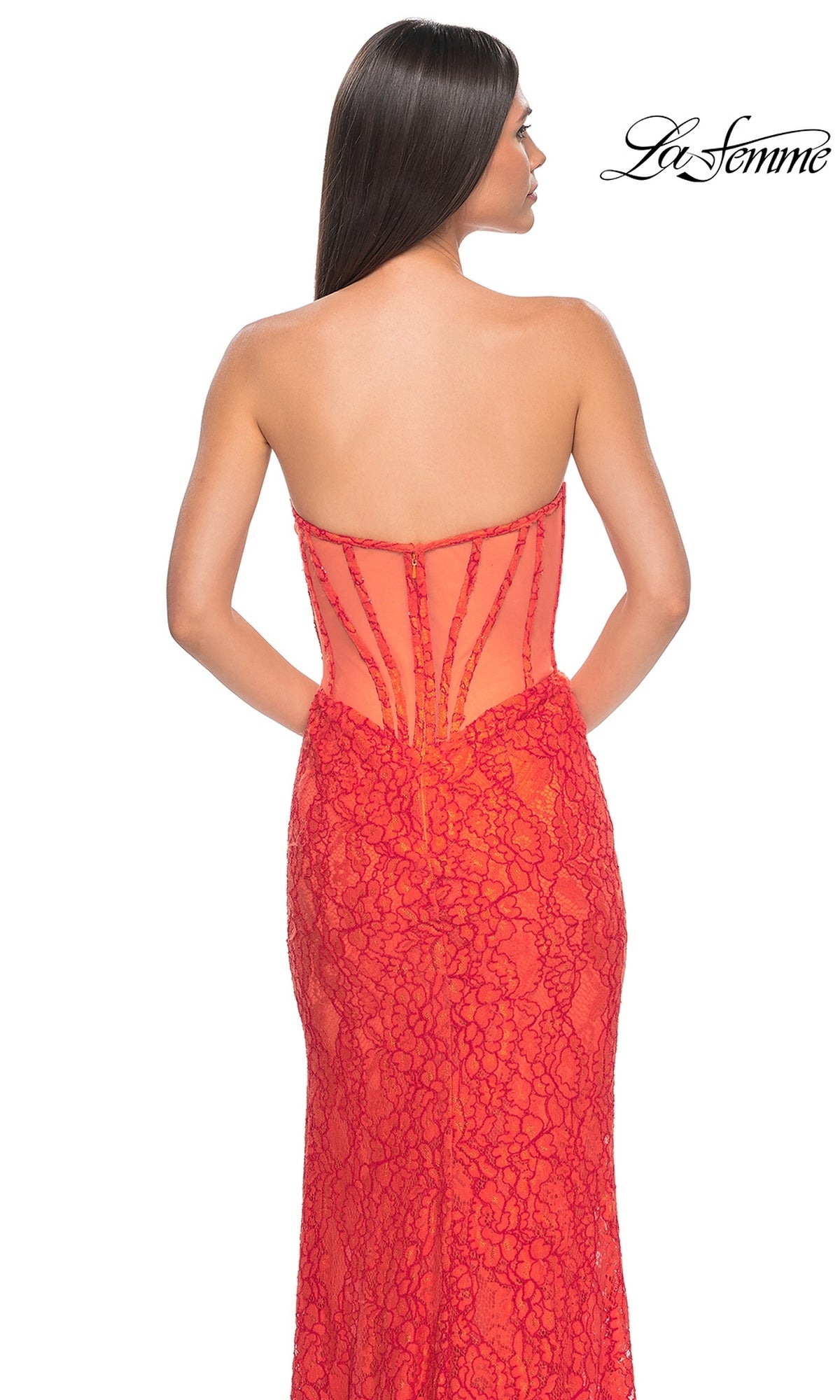 A woman stands facing away from the camera, wearing the La Femme Strapless Long Lace Prom Dress 32298—a fitted red gown with a sheer back panel.